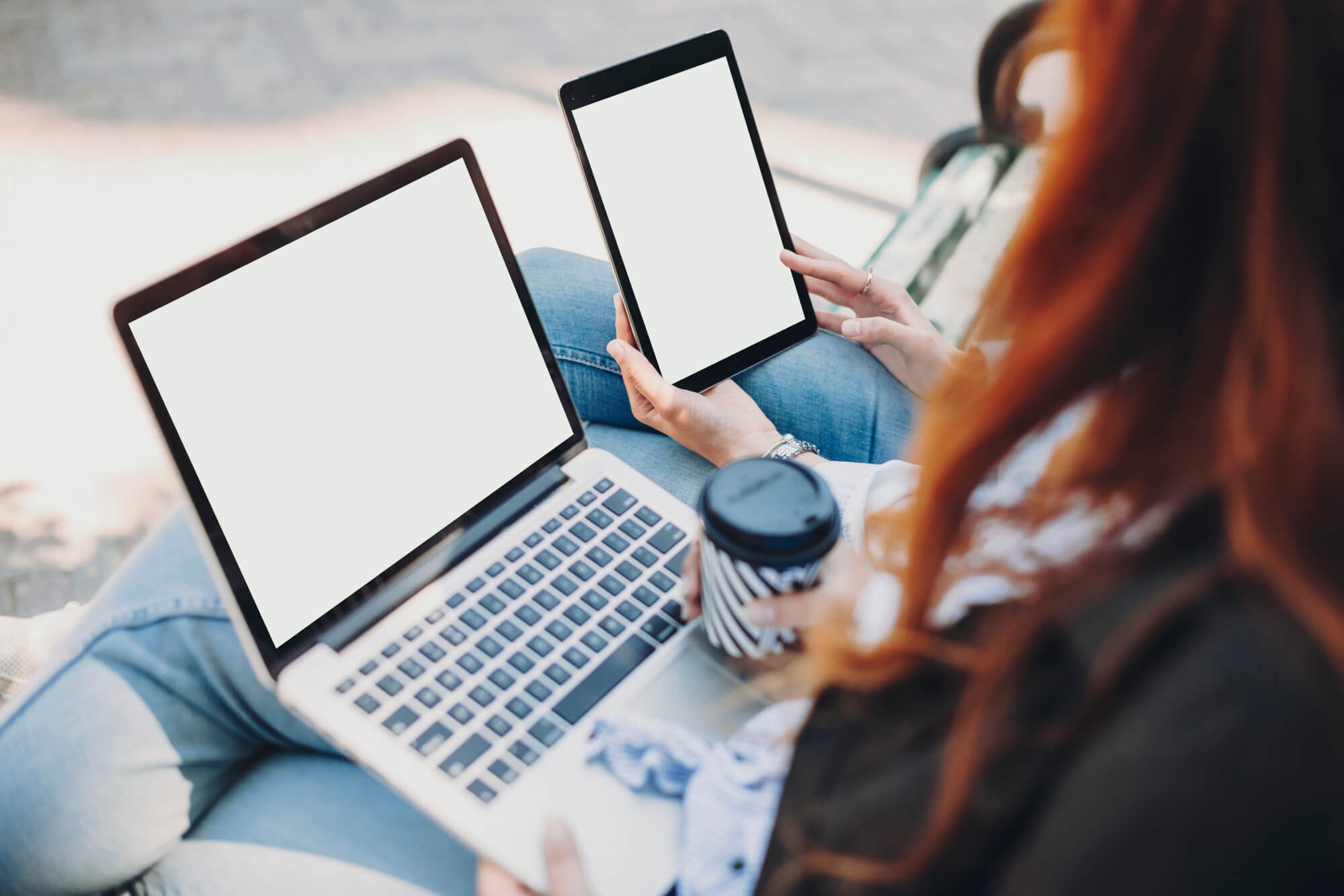 Female hands and legs holding a laptop and a tablet while sittin